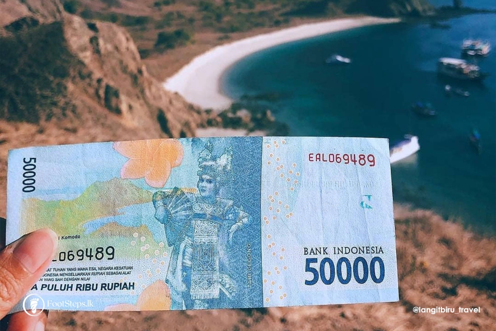 Thing not to do in Bali - A hand holding a 50,000 indonesian rupiah banknote with a scenic coastal background that matches the imagery on the currency.